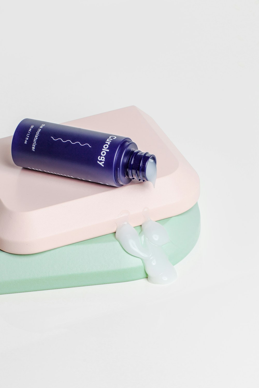 Editorial photograph of simple botanical skincare jars, glass bottles and leaves arranged on a neutral surface, no people